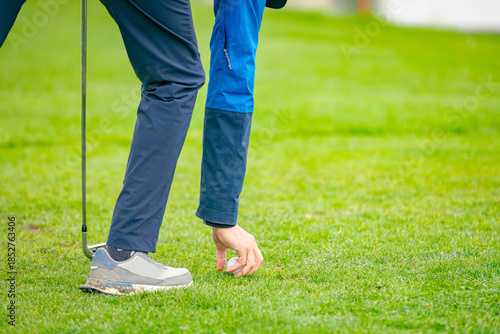 Golfer's hand placing ball on a golf tee