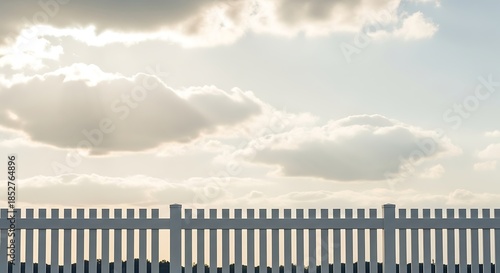 White Picket Fence Against a Cloudy Sky on a Bright Day.