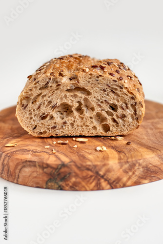 Macro photo of whole grain baguette cut with different seeds lying on a  wooden board , isolated