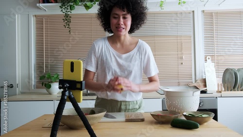 Female food blogger livestreaming a cooking show in her kitchen