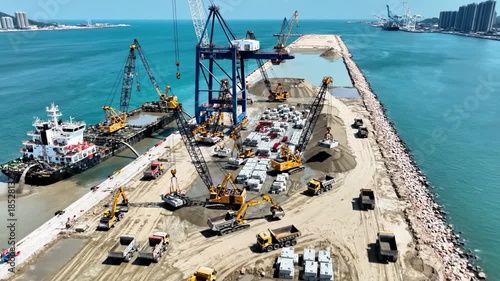 Aerial view of a construction site on a pier with various heavy machinery and vehicles