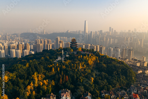 Aerial view of Hong’en Pavilion perched atop a verdant hill, contrasting against the hazy cityscape backdrop, Chongqing, Hong’en Pavilion, China.