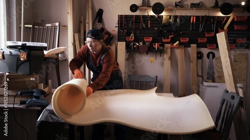 Professional female furniture restorer using foam padding for upholstery renovation in specialized repair workshop