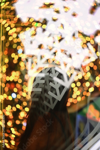Silhouette of a woman with bokeh snowflakes in front of a Christmas tree.