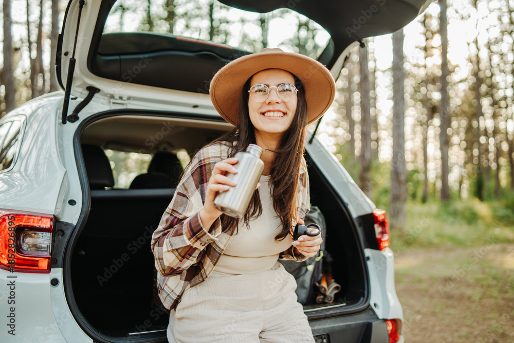 Naklejka premium Woman enjoying travel freedom in forest with reusable bottle