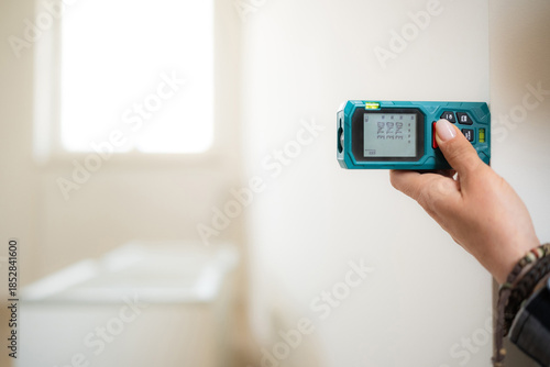 Girl Using A Laser Distance Meter Tool To Measure The Distance From Wall To Wall In A Room