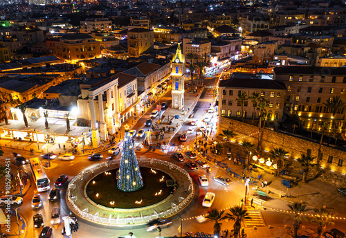 Aerial view of St. Peter church and Jaffa Clock Tower square illuminated with warm lights, contrasting with the dark night sky, Tel Aviv-Yafo, Tel Aviv District, Israel.
