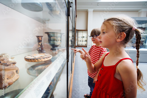 Two kids on excursion observe ancient artifact in glass case