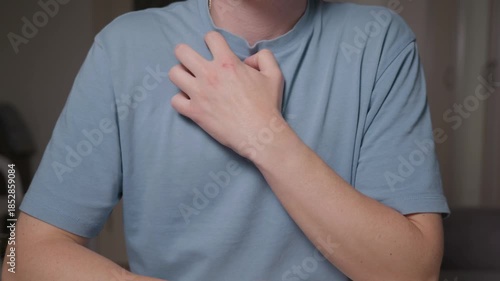 Wallpaper Mural Close up of a man scratching his chest through a t shirt. Focus on hand and fabric without face, showing a casual everyday gesture and natural human behavior. High quality 4k footage Torontodigital.ca