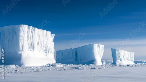 Majestic icebergs rise from a vast frozen landscape under a serene sky