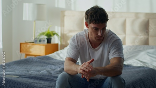 Foto Bored unhappy Caucasian man sitting bed at home suffering pain stressed guy thou