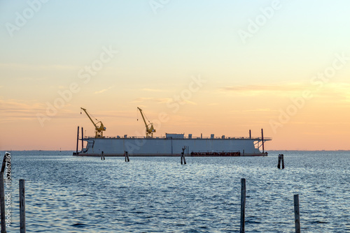 Industrial barge with cranes at sunset in Pellestrina, Venice Lagoon, Italy