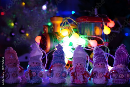 Figures of little angels in knitted sweaters and hats against a background of glowing toys.