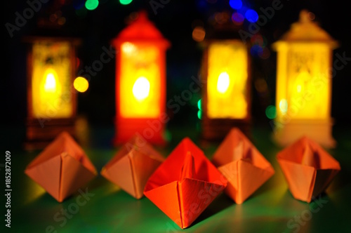 A group of paper boats on a background of glowing lanterns.