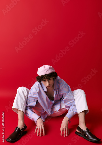 Εκτύπωση καμβά Stylish young man poses creatively against vibrant red backdrop during an artist