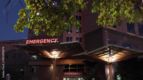 Hospital Emergency Room Entrance with Red Signage. Emergency Sign at Hospital in USA. Emergency Room and Medical Care Building. Hospital, Medical Center, Emergency Room. Evening Night Times.