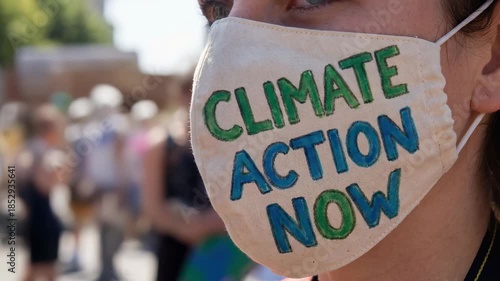 Youth wearing face mask with climate action now message supports passionate climate movement protest outdoors during activism event in daylight