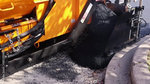 October 14 2025 New York USA Paving machine lays asphalt as truck unloads hot asphalt for road maintenance roadway works