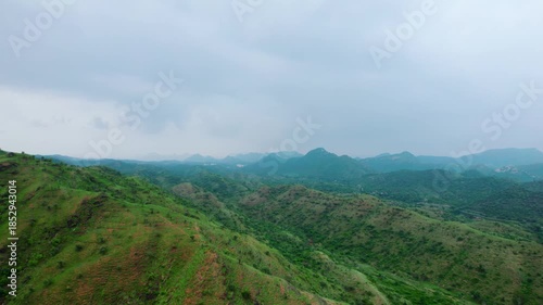 4K Aerial shot of Aravalli range as seen from Rayta in Udaipur, Rajasthan. Green landscape during monsoon season and dark storm clouds in sky. Travel and holidays background. Lush green hills of Arava