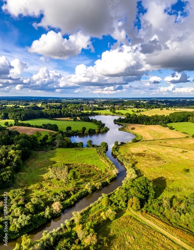 Aerial view of a winding river through vibrant green fields