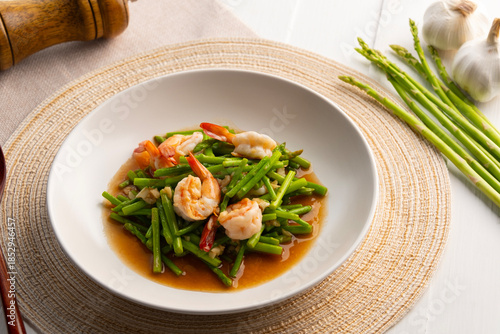 Stir fry asparagus and shrimp with garlic in oyster sauce in white plate.