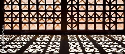 Warm Light Through a Geometric Lattice Window Painting Intricate Shadow Patterns on a Floor.
