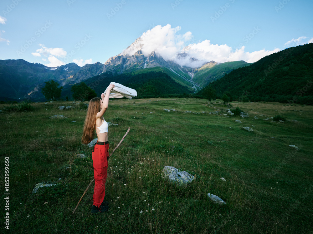 Naklejka premium Girl outdoor scene in mountains field, exploring nature and landscape under blue sky with clouds, breeze over grass and distant peaks, casual clothing and adventure