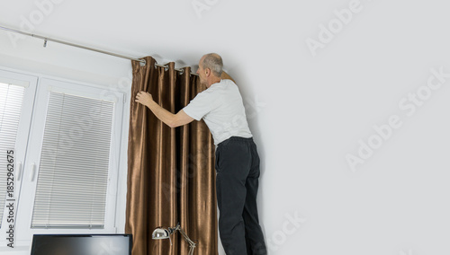 Senior citizen fixing curtain rod. Pensioner standing on the desk. Home accident