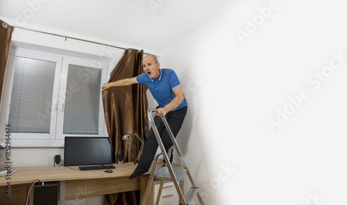 Senior citizen fixing curtain rod. Pensioner standing on the desk. Home accident