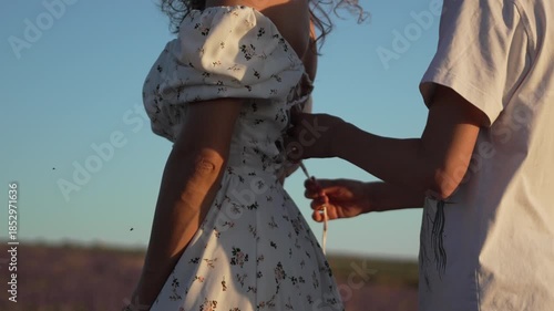 Couple lacing dress corset in lavender field at sunset romantic intimate moment outdoors