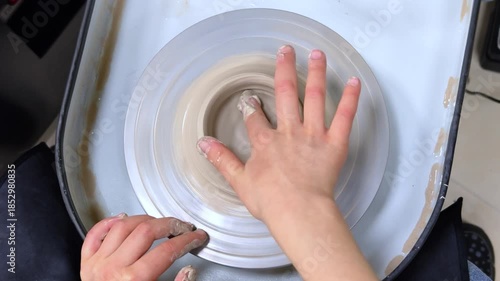 Child making ceramic vase on rotating pottery wheel at workshop. Creativity and traditional crafts concept. 