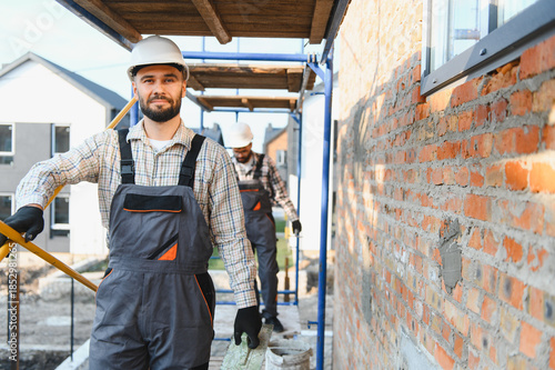Photography Construction workers building brick wall on scaffolding
