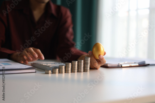 Fotografie Rising stack of coins on the table and golden eggs on businessman ’s hand metaphor for financial planning and investment return