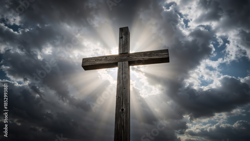 A wooden cross silhouetted against a dramatic sky with sun rays. The Christian symbol of faith, hope, and salvation. Religious concept of resurrection and spirituality