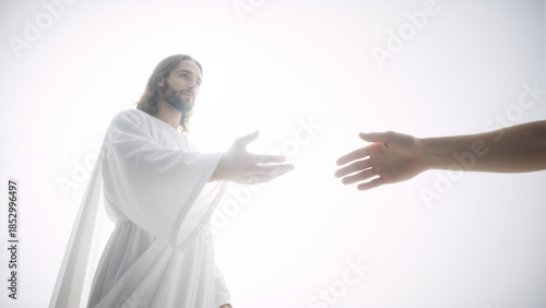 Jesus Christ reaching out a helping hand to a human hand. Divine light background. Religious concept of salvation and faith