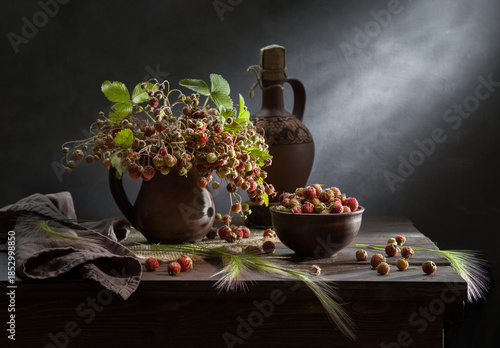 Still life with a bouquet of wild strawberries on a dark background