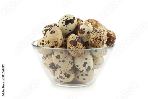 Quail eggs in a glass bowl isolated on white background. Natural patterned farm quail eggs.