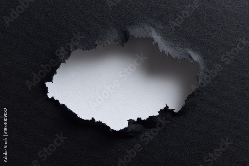 Black paper ripped to reveal white emptiness.  Abstract hole effect. Texture and contrast detail