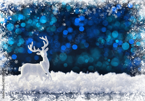 White christmas deer on the snow on a dark festive background. Merry Christmas and Happy New Year.