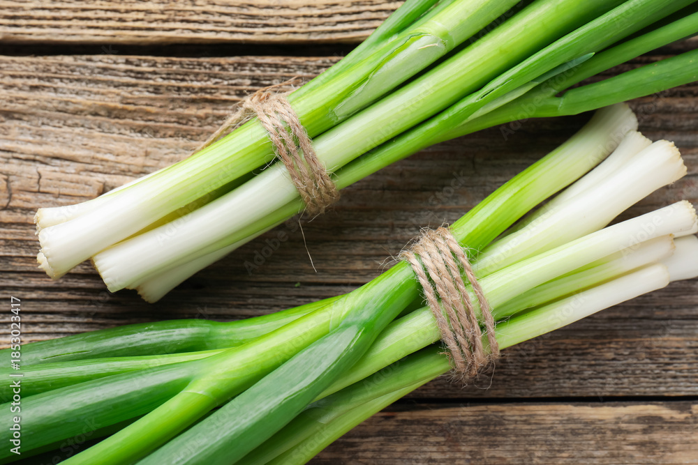 Fototapeta premium Fresh ripe green onions on wooden table, top view