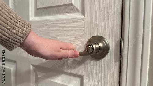 Close up of a woman’s hand jiggling an interior door handle to check if the door is locked. Subtle home security, privacy, and safety concept inside a house.