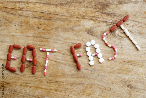 eat fast concept made with pills and clock on wooden background
