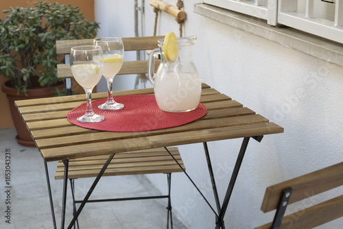 fresh lemonade in pitcher with glasses on an outdoor patio table