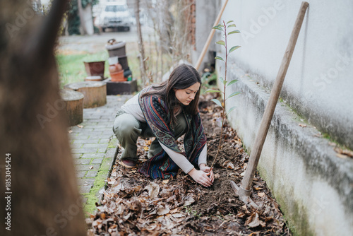 Foto A teenage girl plants a young tree seedling in an outdoor garden bed