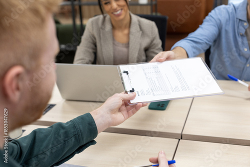Fotografie Business hands exchanging official document on clipboard