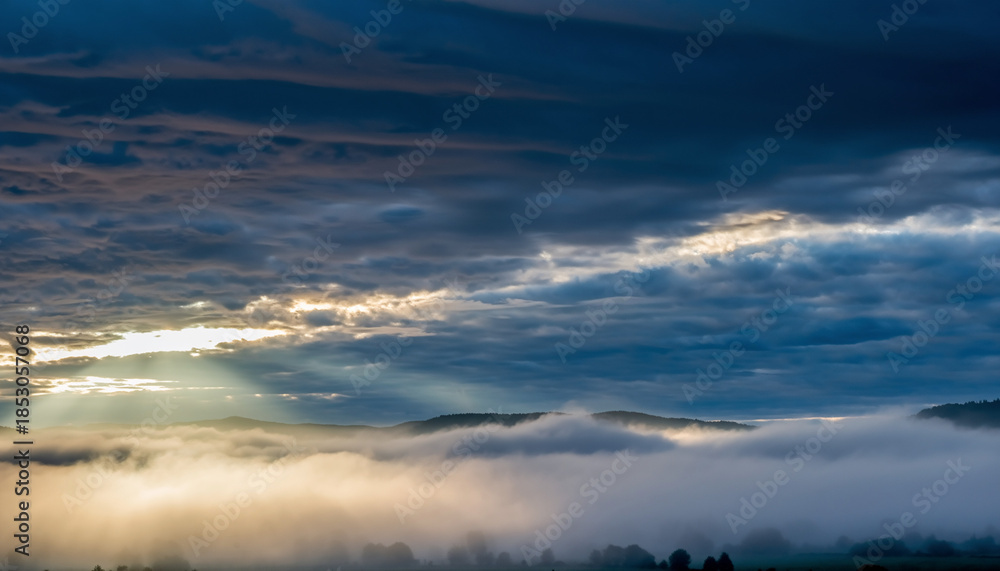 Fototapeta premium brief moonlight breaking through storm clouds, illuminating fog