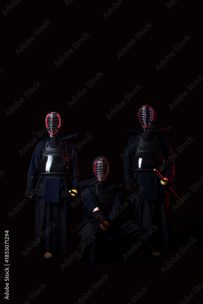 Naklejka premium Professional kendo athlete in uniform posing with shinai sword in black background with blue and red color lighting