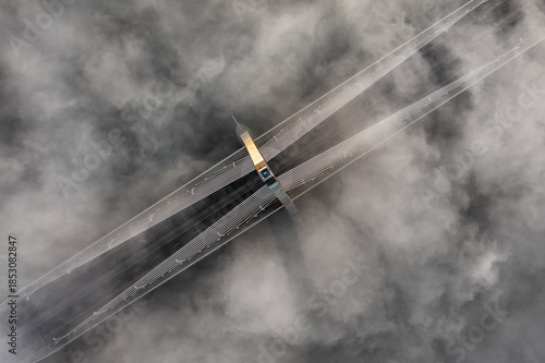 Budapest, Hungary - Aerial view of one of the pillars of the Megyeri Bridge over River Danube on a foggy autumn afternoon with heavy autumn fog bellow and golden shine on the pillar