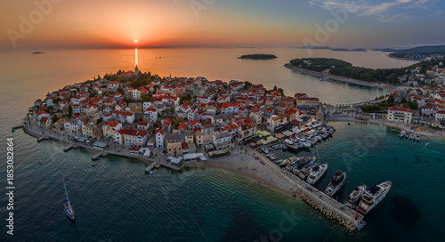 Primosten, Croatia - Aerial panoramic view of Primosten peninsula and old town on a sunny summer afternoon in Dalmatia. Yacht marina, sailboats, setting sun, golden sky at sunset by the Adriatic