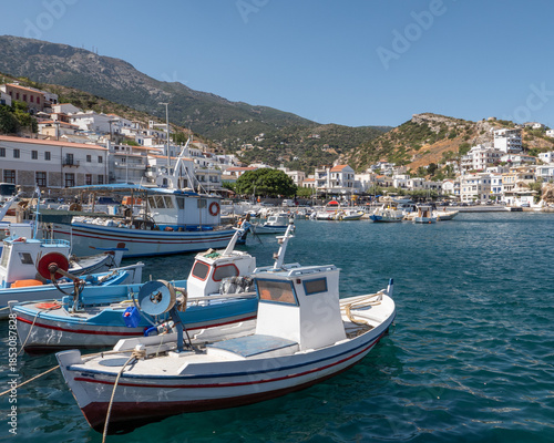Fishing boats in Agios Kirykos harbor, Ikaria, Greece.Traditional fishing boats floating in the harbor of Agios Kirykos on Ikaria island, Greece. Mediterranean port scene with turquoise water and hill